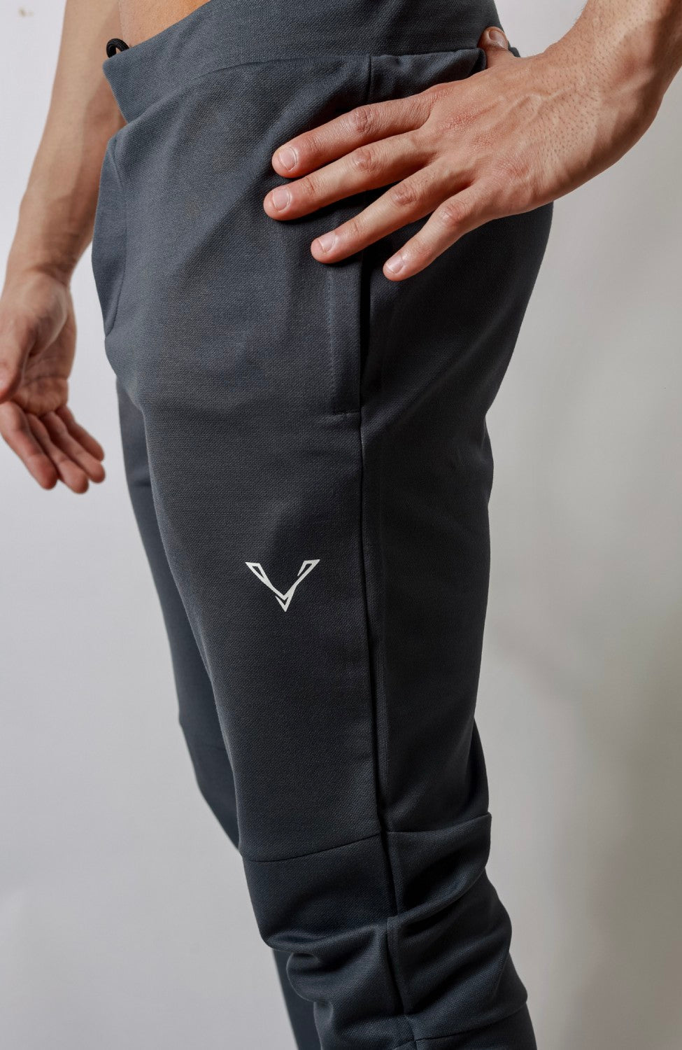 Close-up of dark Vie Dominator joggers showing the side pocket, white logo and knee panel.