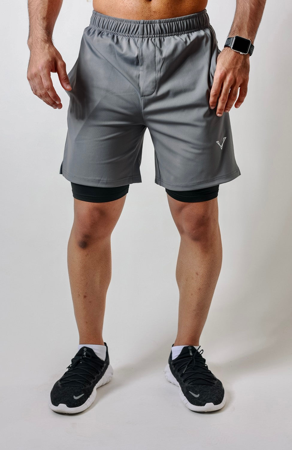Grey Vie Apex shorts worn over an attached black inner layer visible below both leg openings.